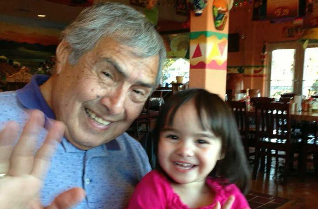 Grandfather and granddaughter smiling at camera