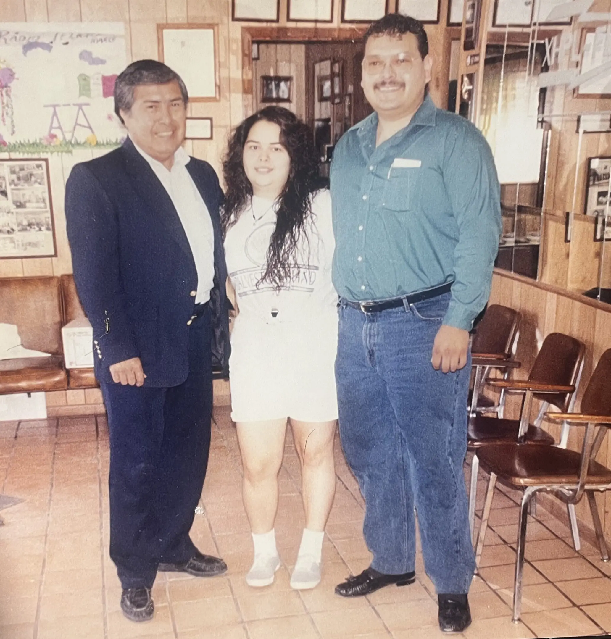 Three people posing in wood-paneled room